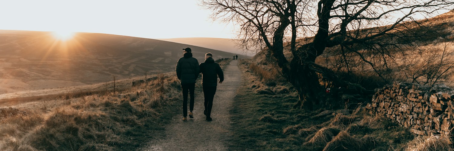 Zwei Menschen gehen nebeneinander auf einem Feldweg