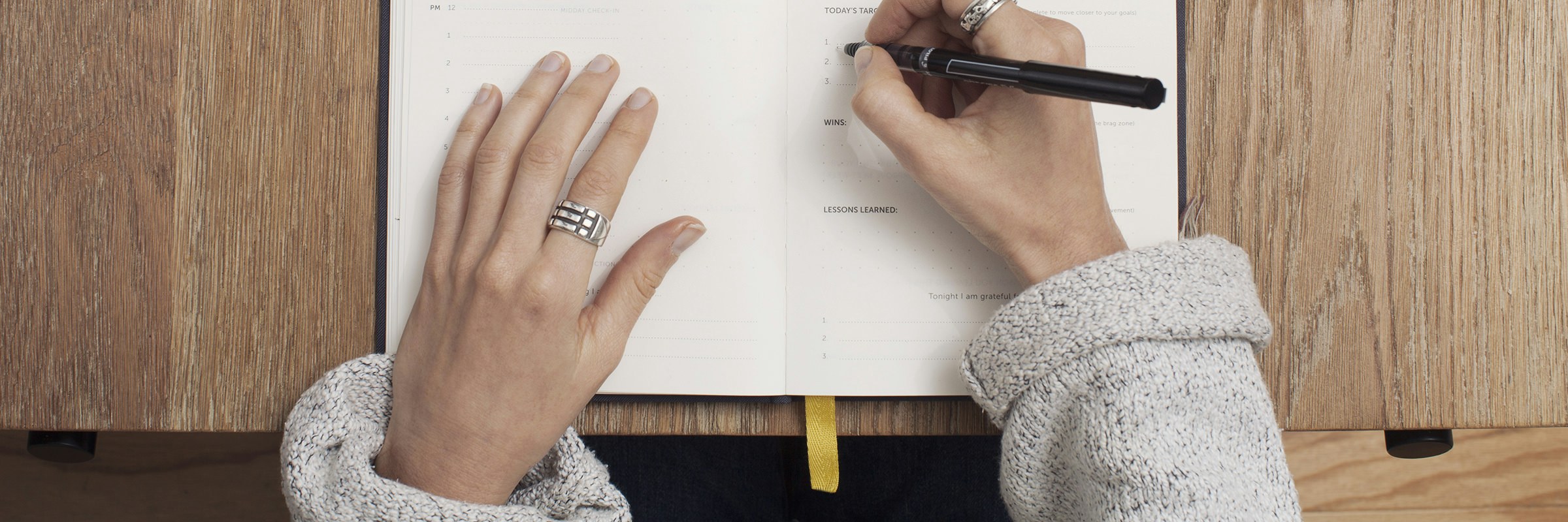 Hand schreibt Notizen in ein aufgeschlagenes Buch